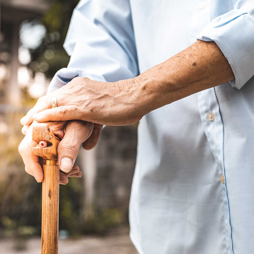 Close up of elderly hands in wrinkles holding walking stick.elde
