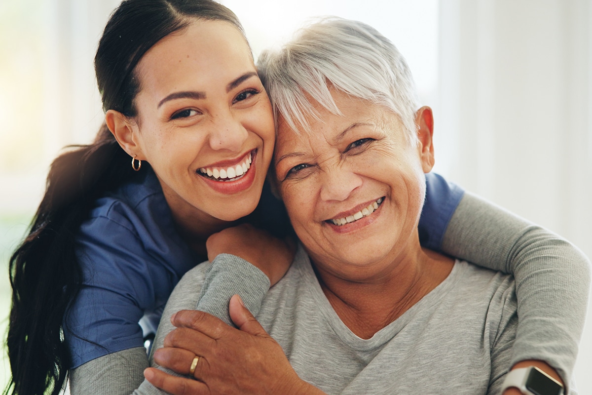 Happy woman, nurse and hug senior patient in elderly care, support or trust at old age home. Portrait of mature female person, doctor or medical caregiver hugging with smile for embrace at house.