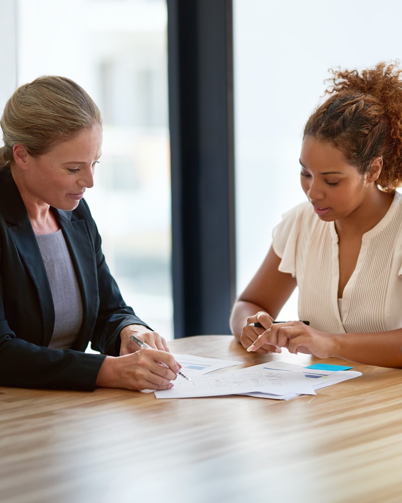 a business professional helps a woman fill out documents