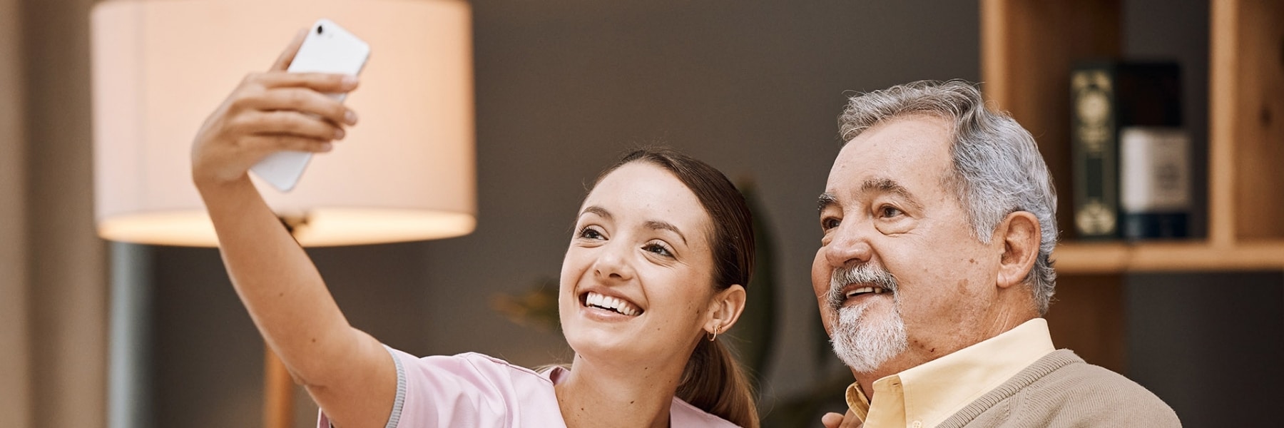 Caregiver taking a selfie with an older man while sitting together