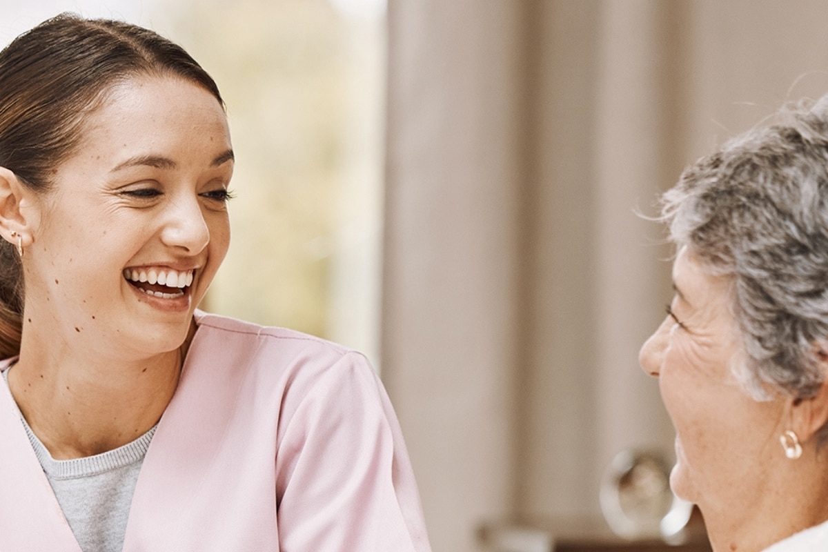 Caregiver sharing a warm moment with an older woman at home