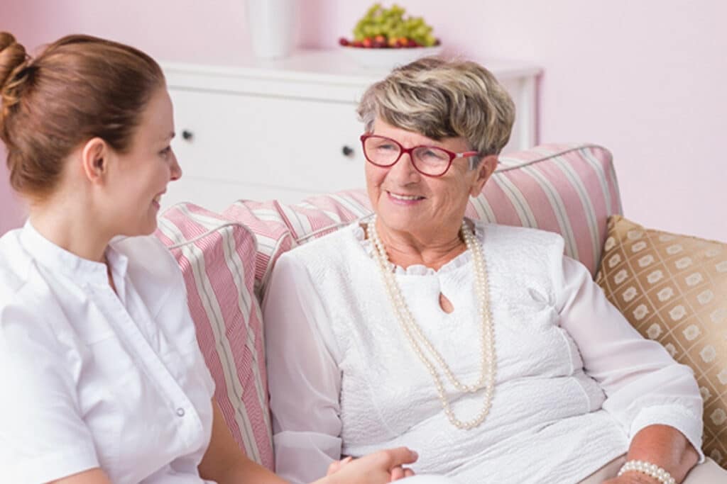 Caregiver talking with an older woman while sitting together at home