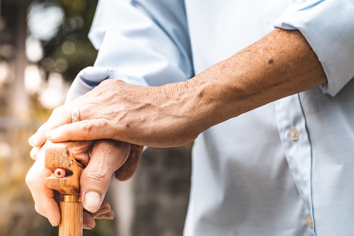 Close-up of an older adult holding a wooden walking cane