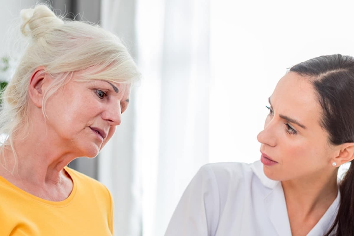 Care professional listening attentively to an older woman at home